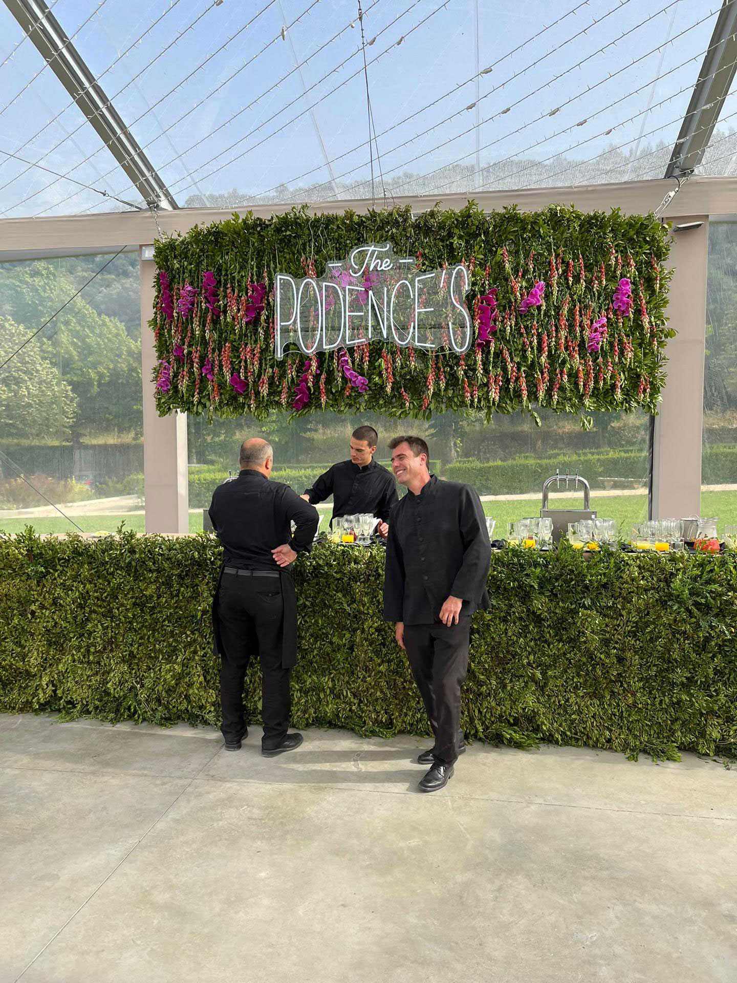 Painel de folhagens cheio de orquídeas e muro inglês na parte de baixo.